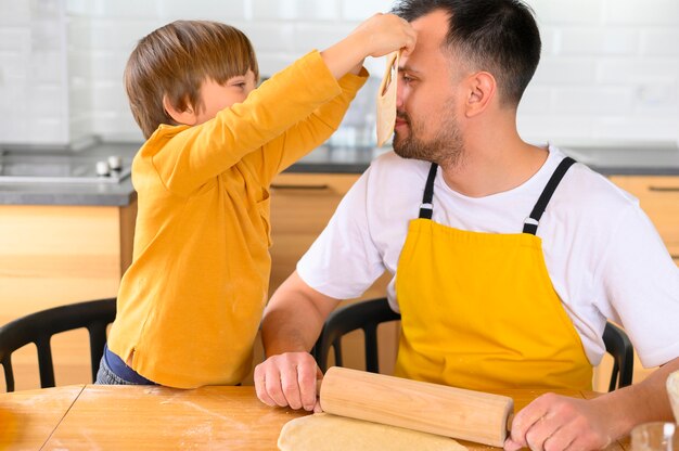 Son puts a dough mask on his father face