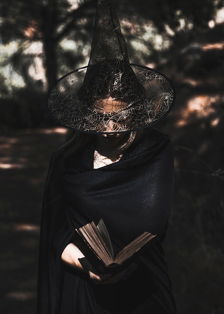 Sorceress reading book in thicket daytime