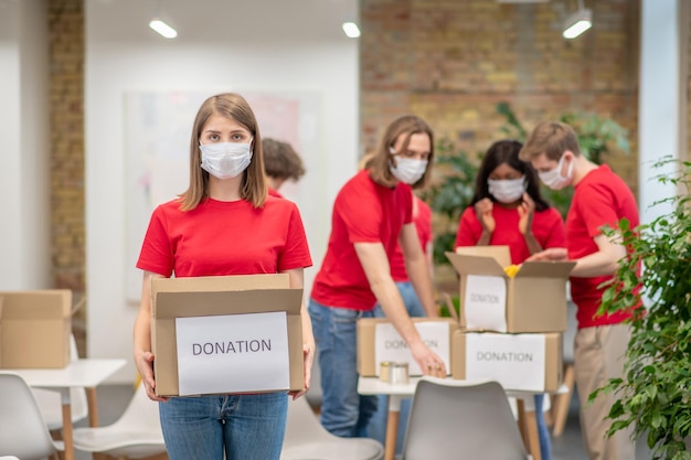 Free photo sorting point. volunteers in facial masks working with donations sorting