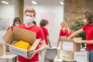 Free photo sorting point. volunteers in facial masks working with donations sorting