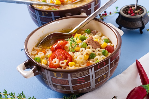 Free Photo soup with small pasta, vegetables and pieces of meat in  bowl on  blue table. italian food.