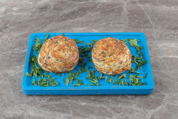 Free Photo sour shor shor gogals and parsley leaves on a blue platter on marble surface