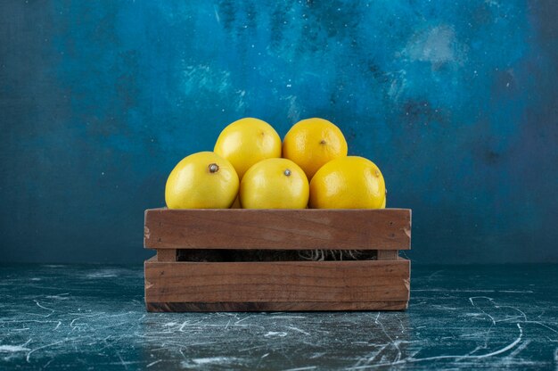 Sour yellow lemons in wooden box. 