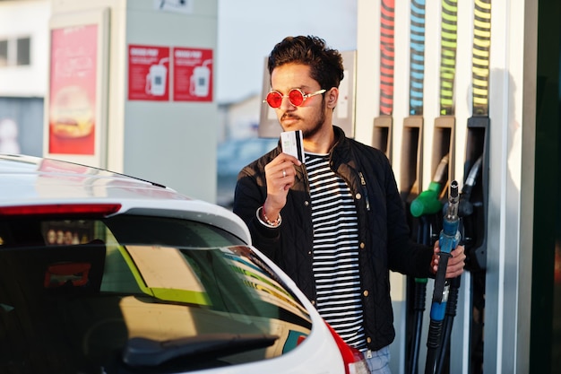 Free photo south asian man or indian male refueling his white car on gas station and hold credit card