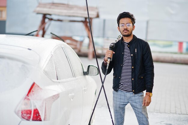 South asian man or indian male washing his white transportation on car wash