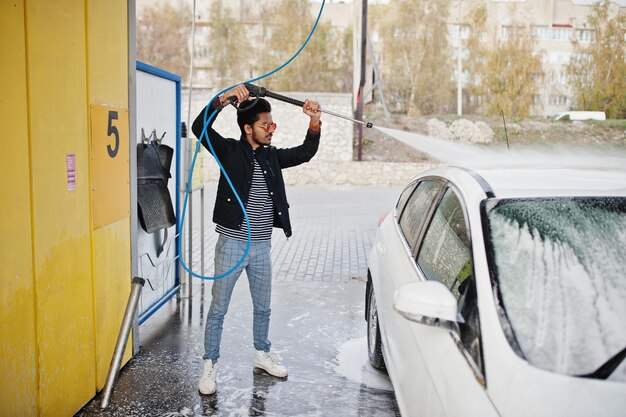 South asian man or indian male washing his white transportation on car wash