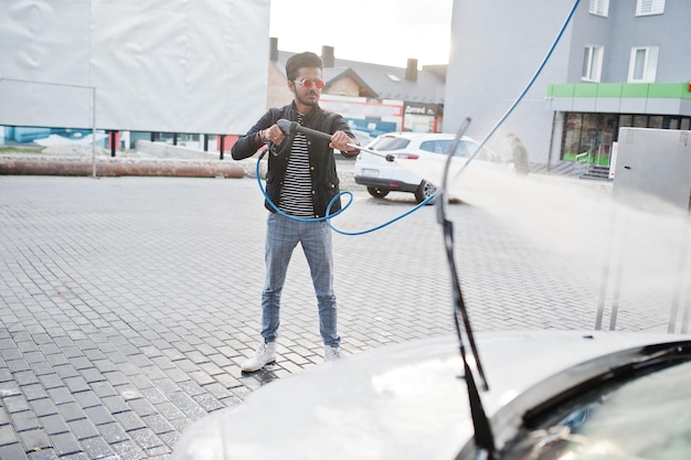 South asian man or indian male washing his white transportation on car wash