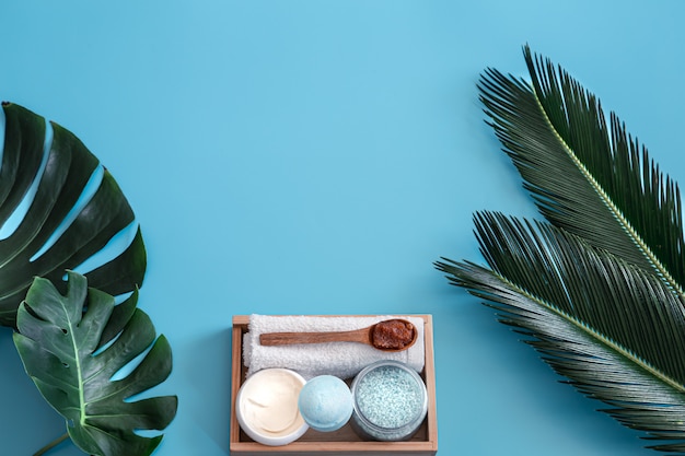 Free photo spa. body care items on blue with tropical leaves.