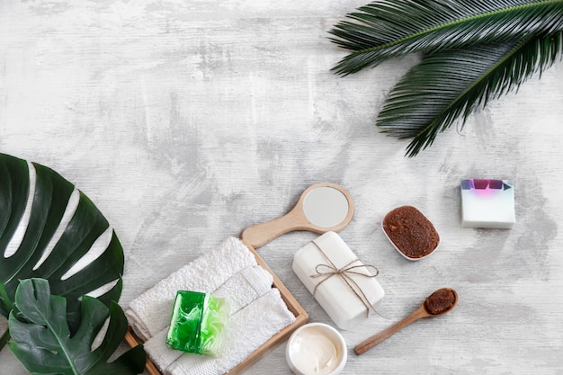 Spa. Body care items on white with tropical leaves.