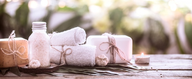 Spa handmade soap with white towels and sea salt, the composition of the tropical leaves with a candle, wooden background