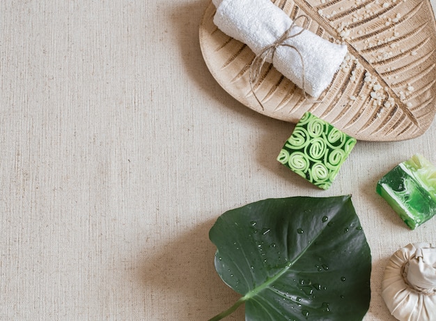 Spa still life with soap, towel, leaf and sprinkled sea salt top view. Hygiene and beauty concept.