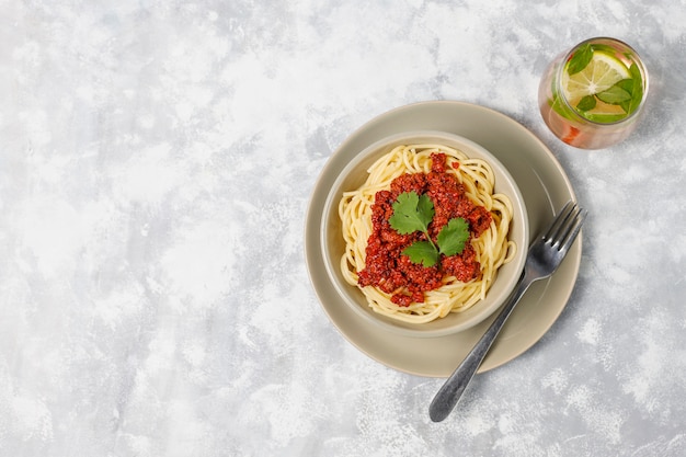 Spaghetti bolognese and lemonade on grey concrete 