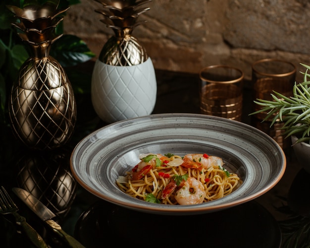 Spaghetti cooked with seafoods and fresh vegetables and served in a grey granite plate