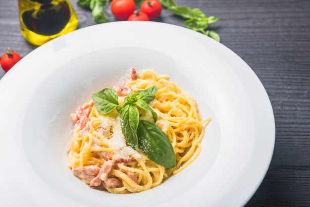 Spaghetti garnish with cheese and bail leaves in a white plate