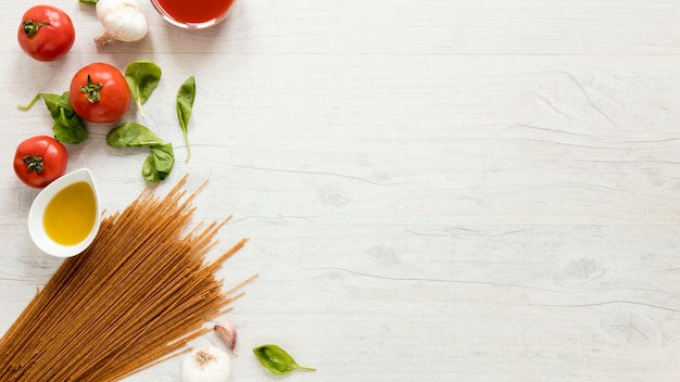 Spaghetti pasta and fresh ingredients over white table