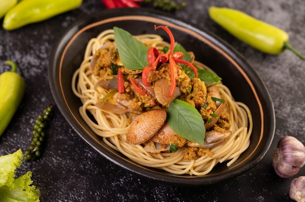 Free photo spaghetti with clams in a black plate with chilies fresh garlic and pepper.