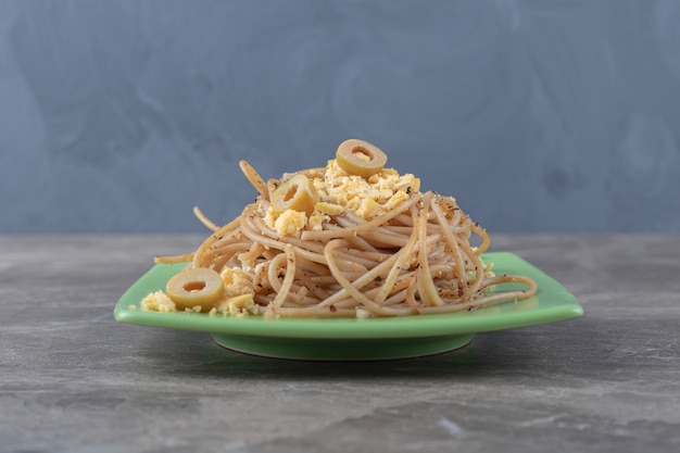 Free photo spaghetti with fried eggs on green plate.