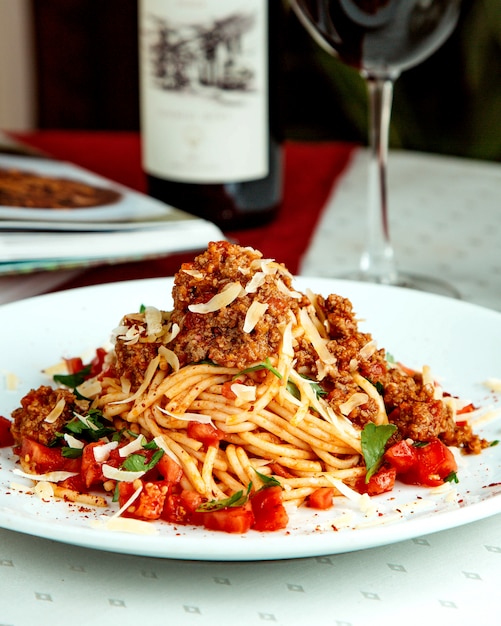 Spaghetti with minced meat tomato cubes cheese and mint