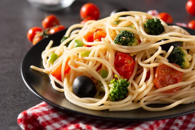 Free photo spaghetti with vegetablesbroccolitomatoespeppers on black slate background