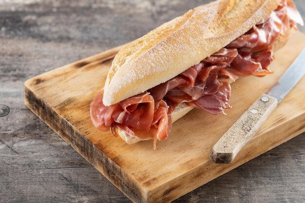 Spanish serrano ham sandwich on wooden table