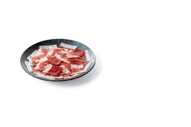 Spanish serrano ham slice on black plate isolated on white background