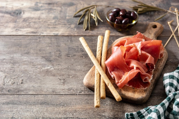 Spanish serrano ham with olives and breadstick