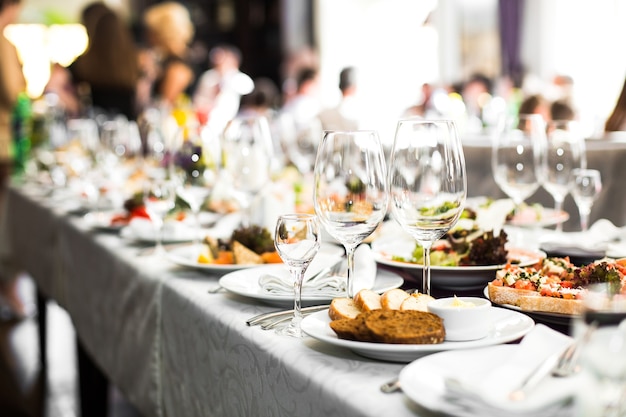 Sparkling glassware stands on long table prepared for wedding di