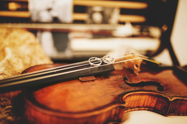 Free Photo sparkling wedding rings lie on the violin strings 