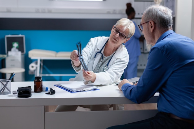 Specialist explaining radiography diagnosis to patient with disease at medical appointment. Healthcare practitioner showing x ray scan results to sick man at annual checkup visit.