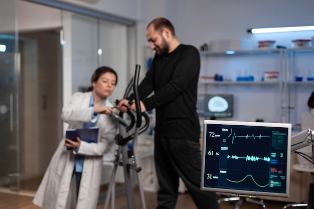 Free photo specialist researcher doctor discussing with sportman in gym training equipment monitoring body endurance during medical workout in modern laboratory. researcher doctor analyzing ekg data