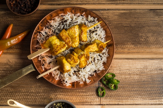 Spices around frying pan with chicken kebab