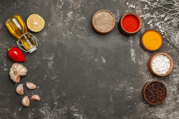 spices garlic red bell pepper bottle of oil and five bowls of spices