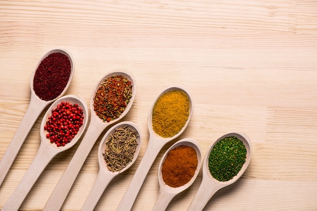 Spices in spoons on wooden table