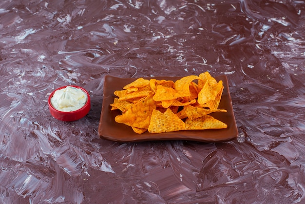 Free photo spicy chips on a plate next to a bowl of mayonnaise , on the marble table.