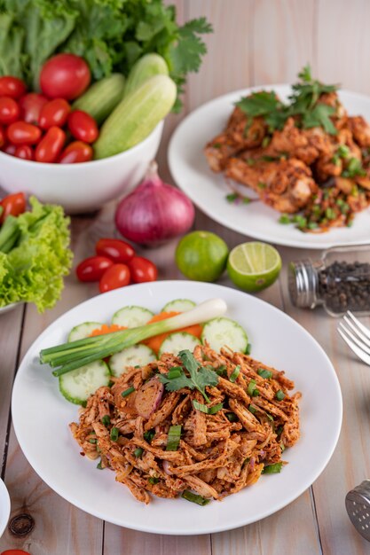 Spicy minced chicken on a white plate complete with cucumber, lettuce and side dishes.