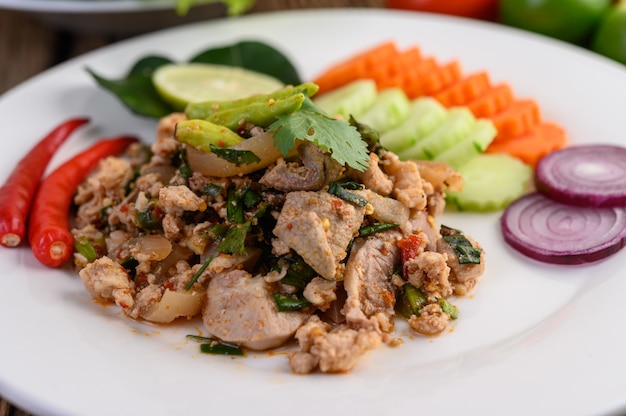 Spicy Minced Pork Salad on a white plate on wooden table.