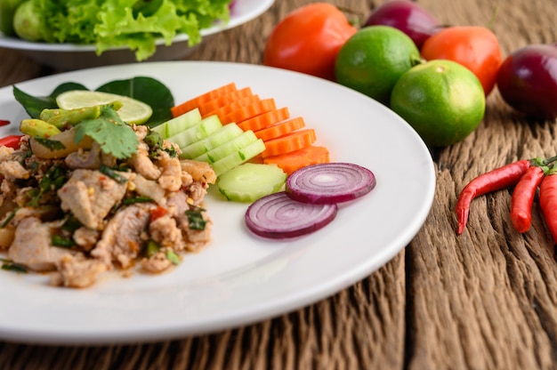 Spicy Minced Pork Salad on a white plate on wooden table.