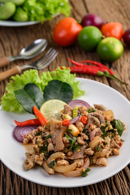 Spicy Minced Pork Salad on a white plate on wooden table.