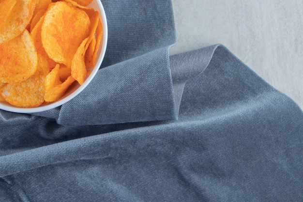 Spicy potato chips and blue cloth on stone.