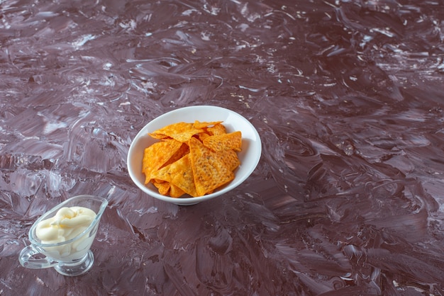 Free photo spicy potato chips in a bowl and yogurt in a glass, on the marble table.