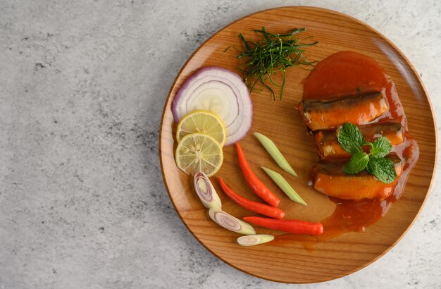 Spicy salad of sardine in tomato sauce on wooden tray