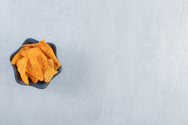 Free photo spicy tortilla chips in dark bowl on stone.