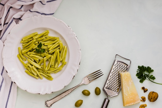 Free photo spinach gemelli pasta on white ceramic plate with ingredients on white backdrop