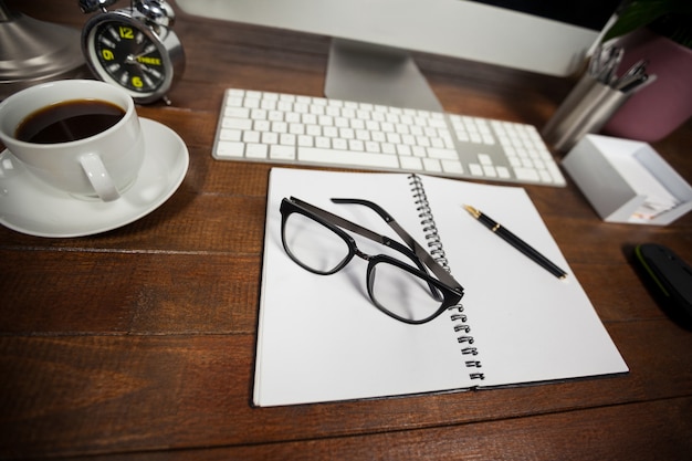 Spiral notepad with black coffee and spectacles