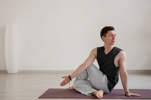 Spiritual young man practicing yoga indoors