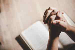 Free photo spirituality and religion, hands folded in prayer on a holy bible in church concept for faith.