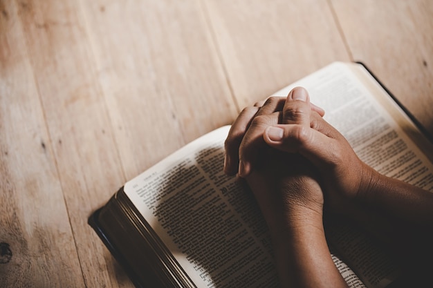 Spirituality and religion, Hands folded in prayer on a Holy Bible in church concept for faith.