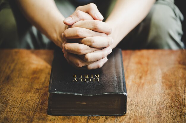 Spirituality and religion, Hands folded in prayer on a Holy Bible in church concept for faith.