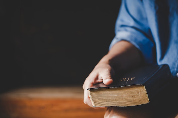 Spirituality and religion, Hands folded in prayer on a Holy Bible in church concept for faith.