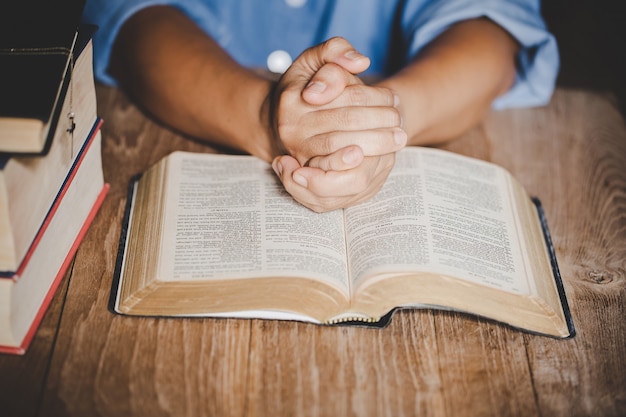 Spirituality and religion, Hands folded in prayer on a Holy Bible in church concept for faith.